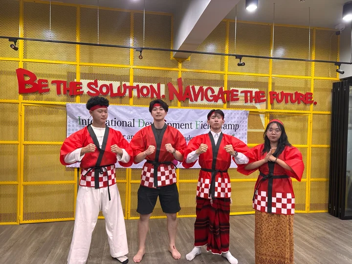 IDFC2026 participants in red happi coats presenting during a cultural exchange