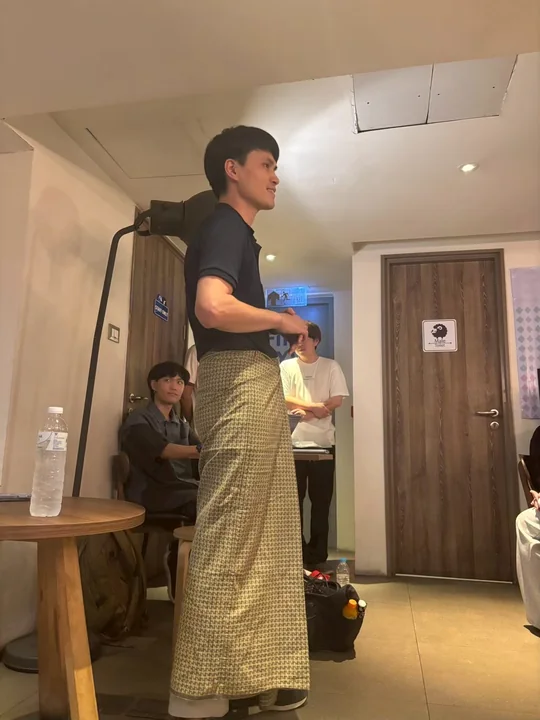 An IDFC2026 participant wearing a longyi and speaking indoors