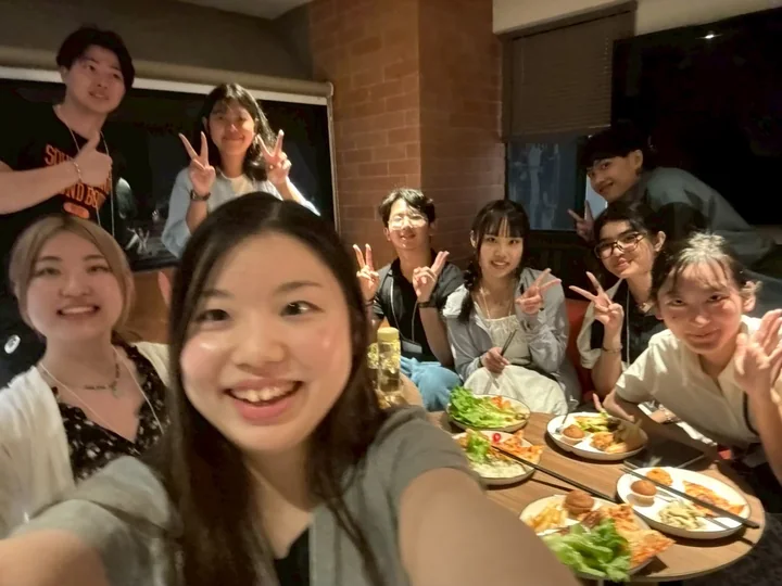 IDFC2026 participants making peace signs for a selfie over a meal